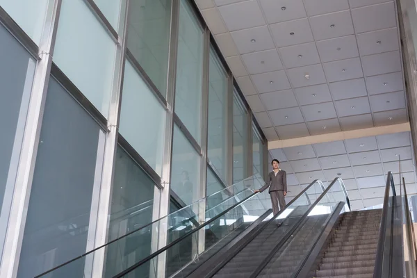 Mujer de negocios asiática parada en escalera mecánica — Foto de Stock