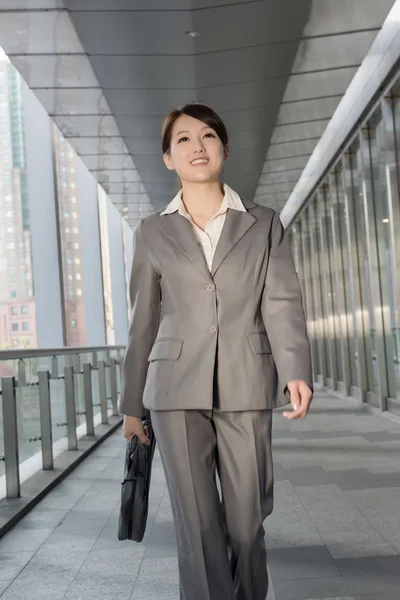 Donna d'affari fiduciosa che tiene la valigetta e cammina — Foto Stock