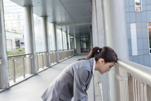 Yorgun Asya iş kadın başının korkuluk koy. — Stok fotoğraf