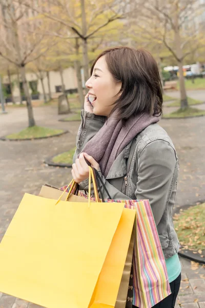 Azjatycki dama dyskusja na telefon trzymać torby na zakupy — Zdjęcie stockowe