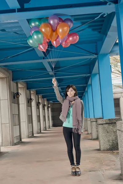 Elegante Aziatische schoonheid bedrijf ballonnen onder brug — Stockfoto