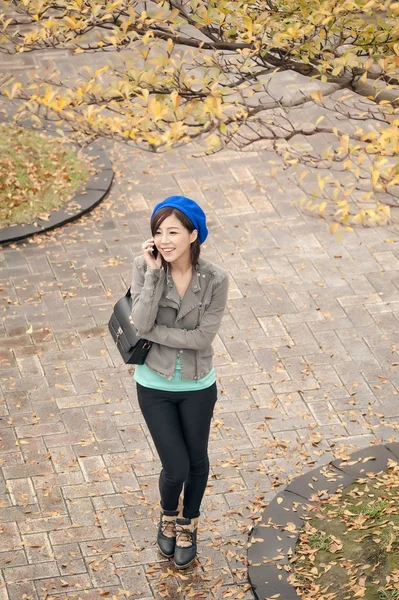 公園内の道路で携帯電話で話している陽気なアジアの女性, — ストック写真
