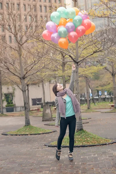 Junge Frau spielt und hält Luftballons — Stockfoto