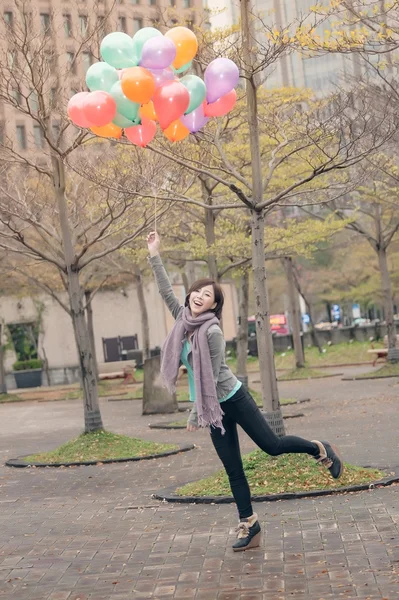 Mujer joven jugando y sosteniendo globos — Foto de Stock