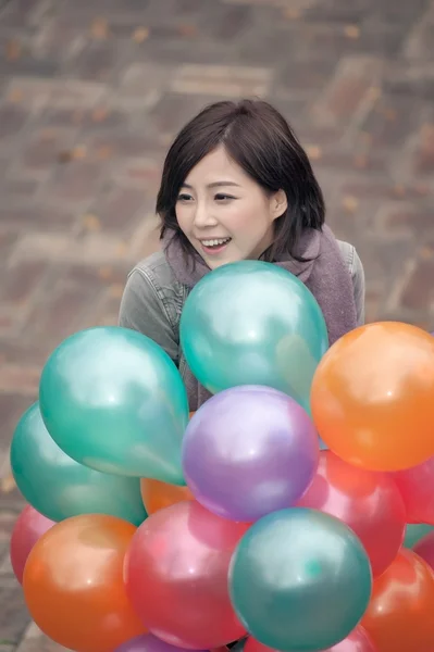 Mujer joven jugando y sosteniendo globos — Foto de Stock