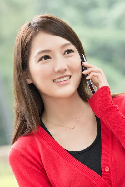Улыбающаяся азиатская молодая женщина отвечает на звонок — стоковое фото