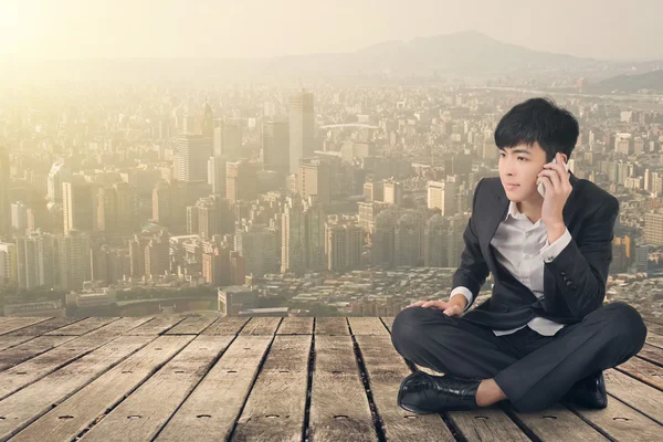 Азиатский бизнесмен принимает вызов и садится на землю — стоковое фото