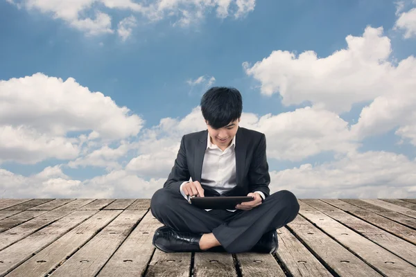 Asiatico business uomo utilizzando pad e sedersi su terra — Foto Stock