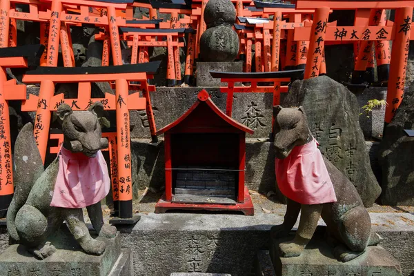 Estátuas de raposa de pedra e muitos pequenos torii . — Fotografia de Stock