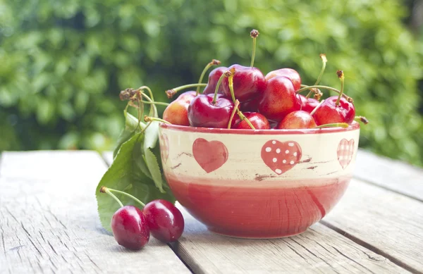 Cherries in a bowl on old wood — Stock Photo, Image