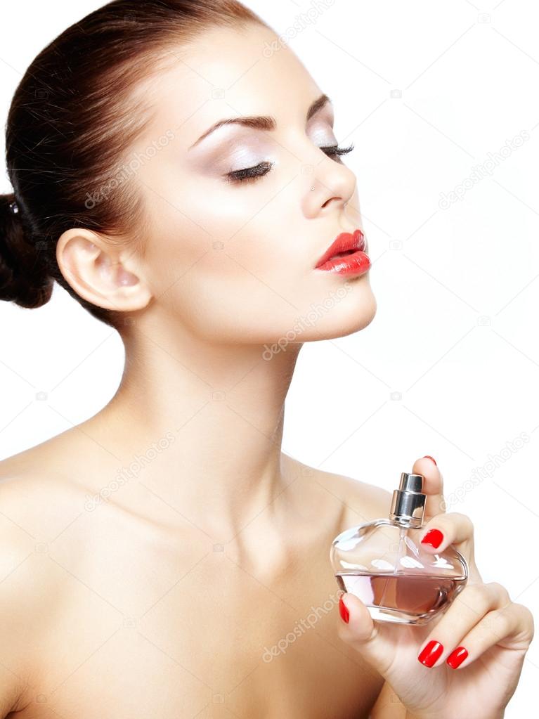 Young woman applying perfume on herself isolated on white backgr