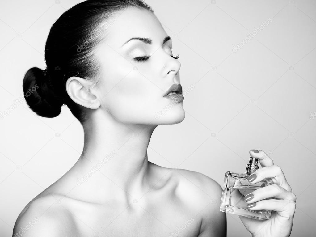 Young beautiful woman with bottle of perfume. Perfect Makeup
