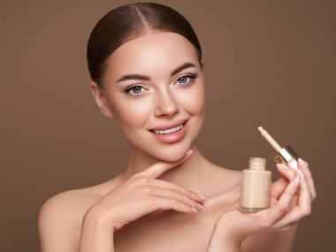 Temiz tenli güzel bir genç kadın portresi. Makyaj şişesi olan bir model. Kozmetik, güzellik ve kaplıca