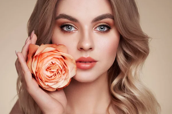 一个漂亮的年轻女子 有着闪亮的波浪般的金发 模型与健康的皮肤 紧密的肖像 带着玫瑰花的女孩 — 图库照片