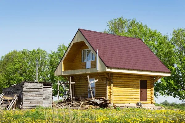 Houten huis in de weide met paardebloemen — Stockfoto