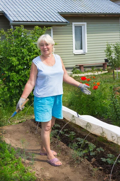 Ältere Frau steht mitten im Garten — Stockfoto