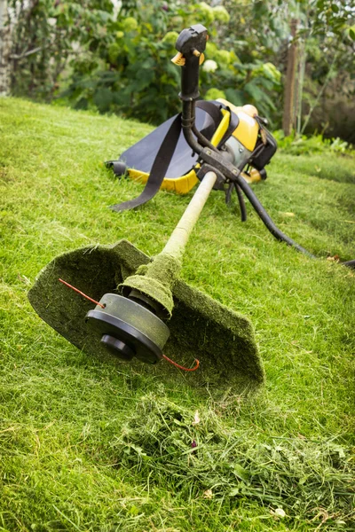 Petrol trimmer on the sloped lawn — Stock Photo, Image