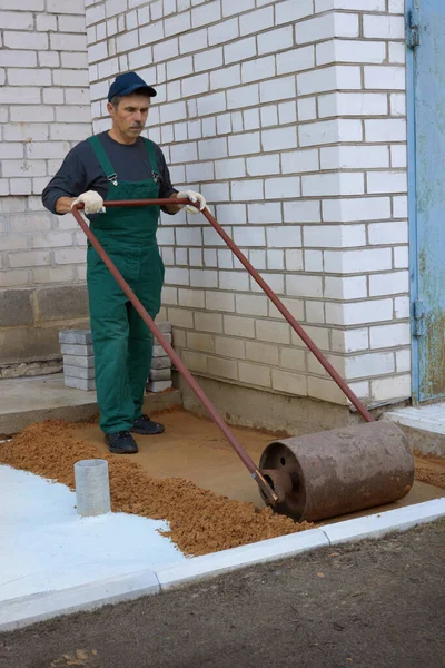 Robotnik Kompaktuje Piaszczystą Glebę Wałkiem Ręcznym Przed Budową Chodnika — Zdjęcie stockowe