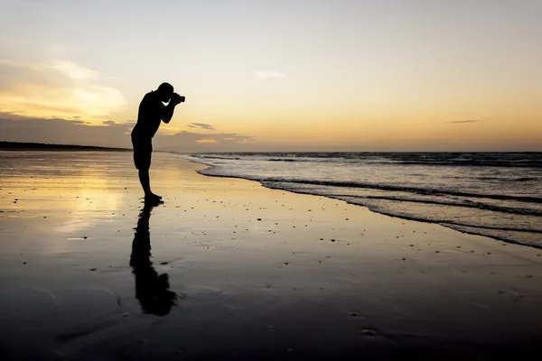 Fotógrafo na praia do pôr do sol — Fotografia de Stock