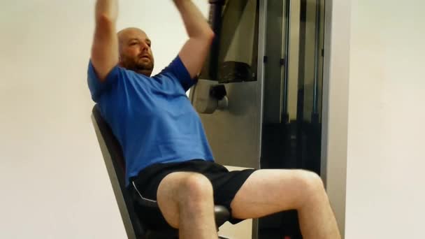 Adult man uses home gym equipment to strengthen his chest muscles. — Stock Video