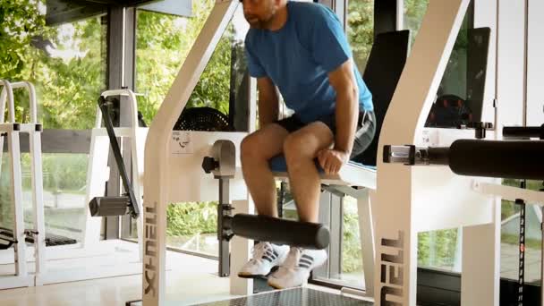 Gimnasio gimnasio interior con pesos de entrenamiento de hombre joven con piernas — Vídeo de stock