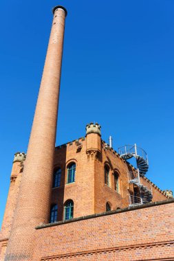 Merdiveni ve kulesi olan kırmızı tuğlalı bir bina.