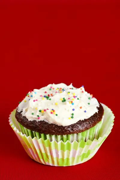 Un cupcake de chocolate esmerilado sobre rojo — Foto de Stock