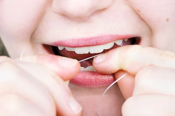 Mujer joven usando hilo dental —  Fotos de Stock