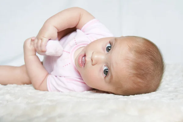 Menina bebê segurando pé — Fotografia de Stock