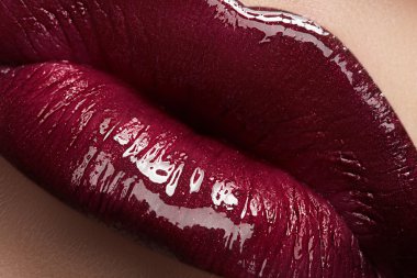 Kadının dudakları parlak moda koyu kırmızı parlak makyaj ile yakın çekim. Makro lipgloss kiraz makyaj. seksi öpücük