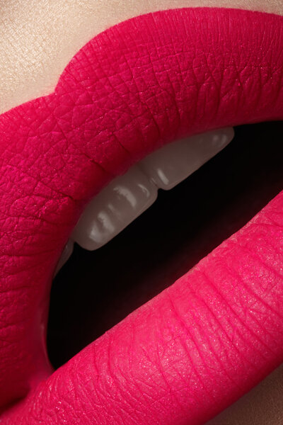 Close-up of beautiful full woman's lips with bright fashion mat pink makeup. Macro shot with magenta frosted lip make-up