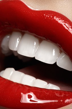 Kadının dudakları parlak moda kırmızı parlak makyaj ile close-up. Makro kanlı lipgloss makyaj