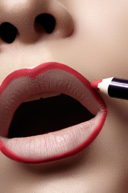 Kadın dolgun dudaklar dudak kalemi ile closeup. Profesyonel makyaj sanatçısı dudak liner için mükemmel makyaj kontur uygulamak. Moda makyaj