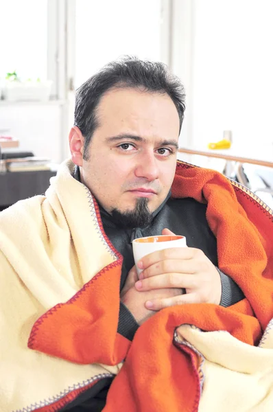 Człowiek z gorączką, trzymając kubek herbaty — Zdjęcie stockowe