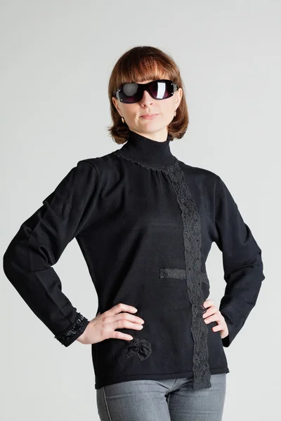 Woman in sunglasses standing with arms akimbo