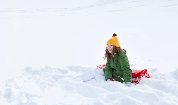 Mädchen mit Schlitten sitzt im Schnee — Stockfoto