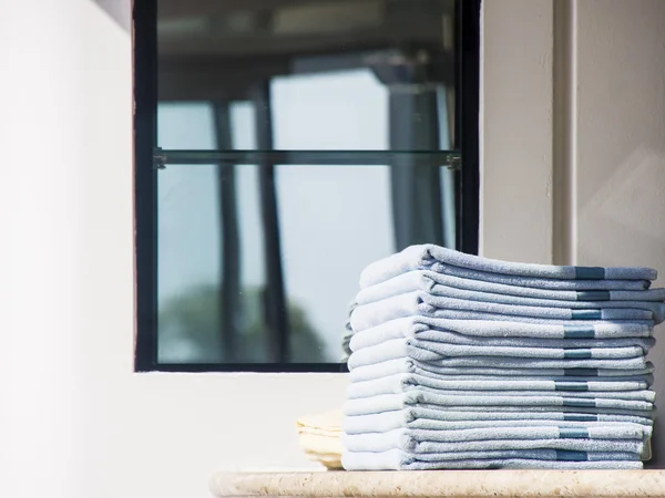 Stapel blauwe handdoeken op het dek van venster — Stockfoto
