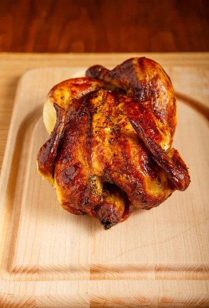 Целый жареный цыпленок на древесины резки доска и стол — стоковое фото