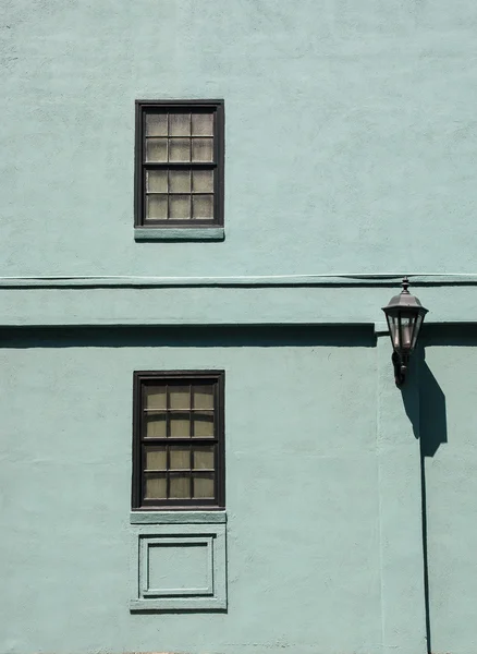Два окна и лампа на старой зеленой стене — стоковое фото