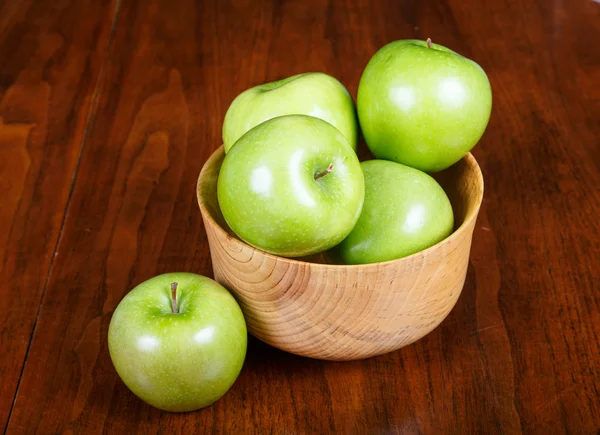 Чаша зеленых яблок с одним на столе — стоковое фото