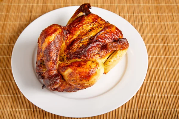 Ψητό κοτόπουλο υπό γωνία σε λευκό πιάτο και χαλί μπαμπού — Φωτογραφία Αρχείου