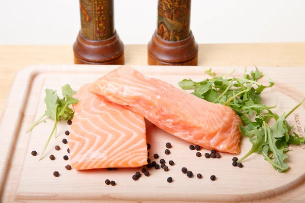 Filetes de salmón a bordo con granos de pimienta y rúcula —  Fotos de Stock