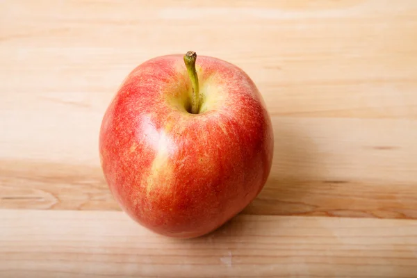 Einzelner roter Apfel auf einem Holzschneidebrett — Stockfoto