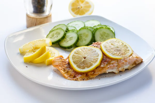 Запеченный лосось с нарезанными лимонами и огурцами — стоковое фото