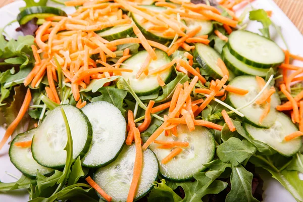 Gesneden komkommers en geraspte wortelen op salade — Stockfoto