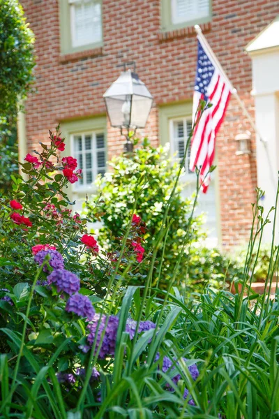 Американский флаг на кирпичном доме за садом — стоковое фото