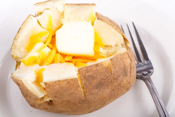 Pomme de terre cuite au four sur une assiette avec beurre et fromage — Photo