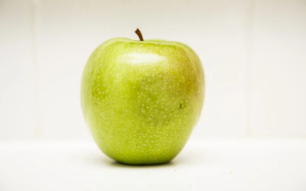 Manzana verde entera en contador blanco — Foto de Stock