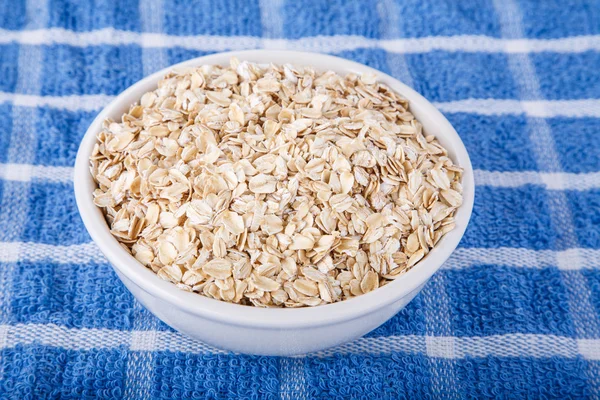 Dry Oatmeal in White Bowl on Blue Towel — Stock Photo, Image