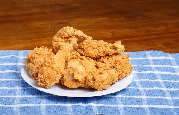 Frisches gebratenes Huhn auf blau kariertem Tischset und Holztisch — Stockfoto